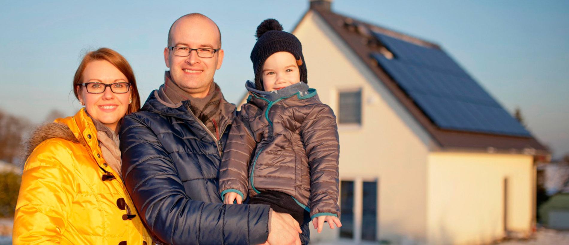 Familie: Mutter, Vater und Sohn vor dem Haus, mit PV-anlage, glücklich mit Stromspeicher