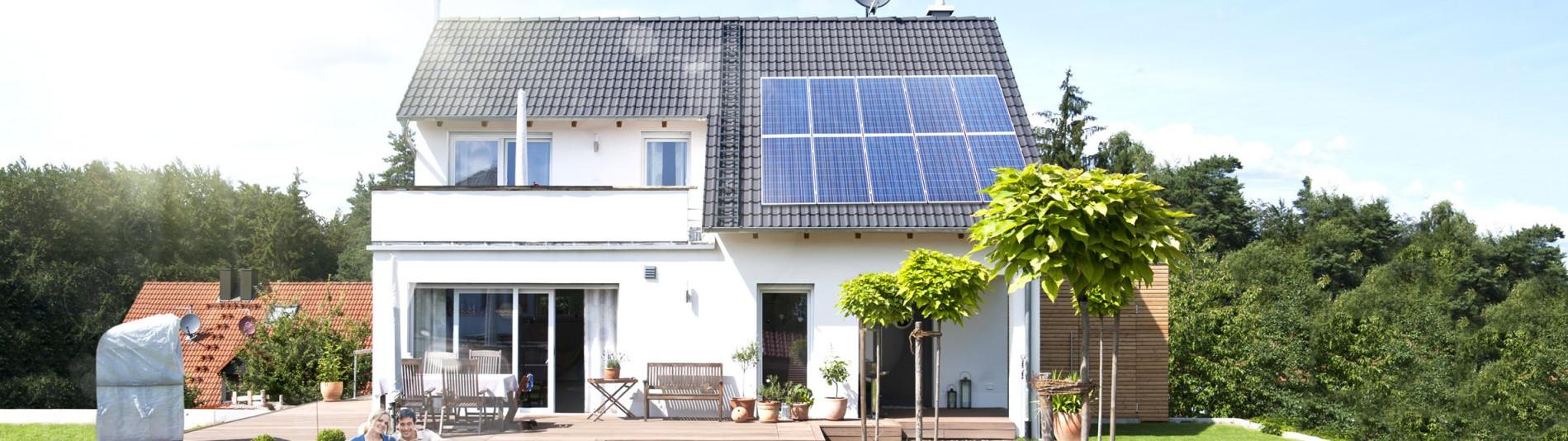 Familie sitzt im Garten auf der Wiese an einem sonnigen Tag und macht sich unabhängig und autark mit Heimspeicher sonnenBatterie und einer PV Solar Anlagae