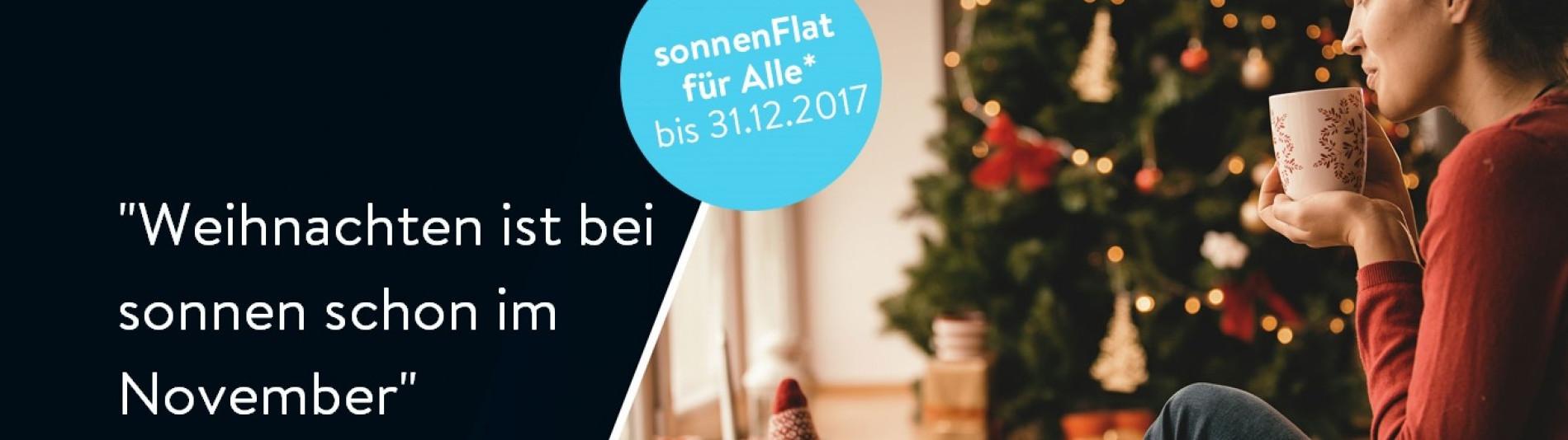 Frau vor Weihnachtsbaum trinkt Tee und freut sich an der sonnenFlat teilnehmen zu können und sich somit unabhängig und autark zu machen