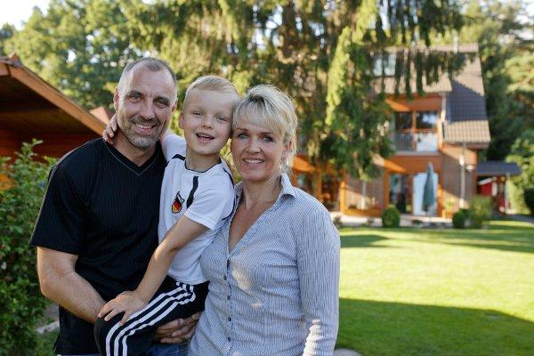 Familie im Sommer im Garten vor dem Haus mit PV-Anlage 