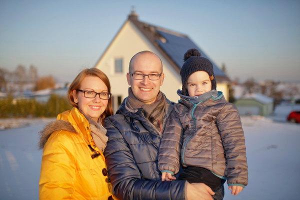 Familie vor dem Haus, mit Solaranlage und Heimspeicher