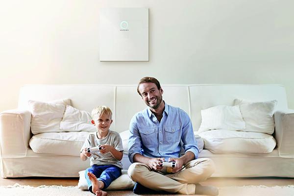 wohnzimmer mit vater und sohn beim gaming vor einem solarspeicher