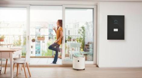 Frau am Fenster macht sich unabhängig mit einem Energiespeicher sonnenBatterie und senkt somit ihre Kosten 