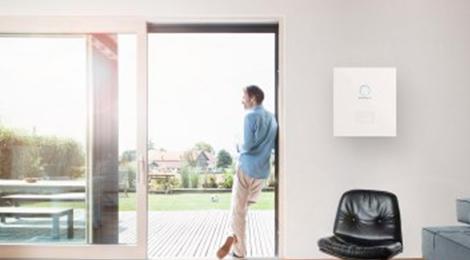 Mann am Fenster in seiner Wohnung macht sich unabhängig mit Solarstromspeicher sonnenBatterie 
